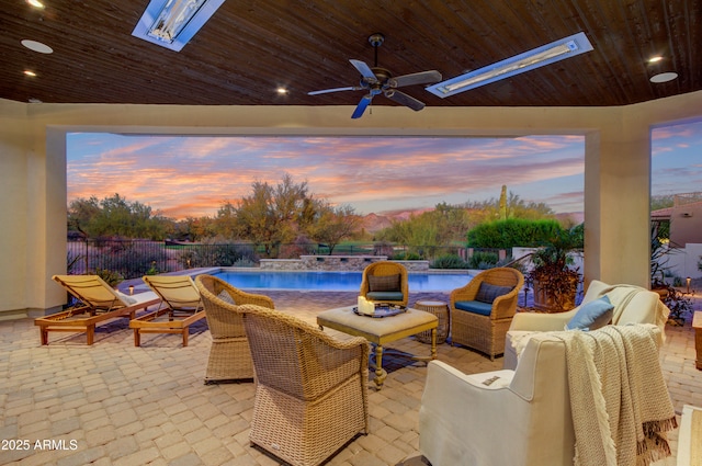 patio terrace at dusk featuring pool water feature, an outdoor living space, a fenced in pool, and ceiling fan