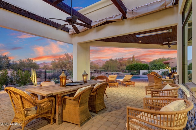 patio terrace at dusk featuring ceiling fan and a fenced in pool