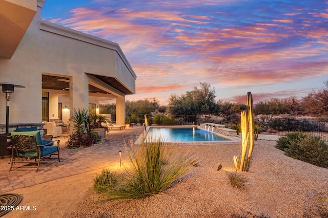 pool at dusk featuring a patio area