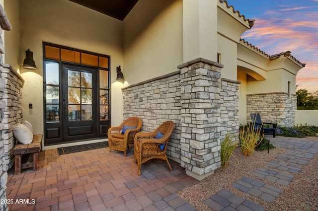 exterior entry at dusk featuring french doors and a patio area