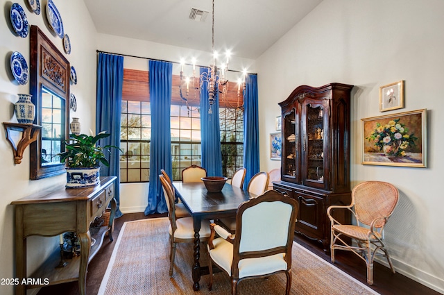 dining area with dark wood-type flooring and a chandelier