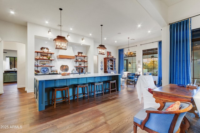 kitchen with a kitchen breakfast bar, pendant lighting, light hardwood / wood-style flooring, and a large island