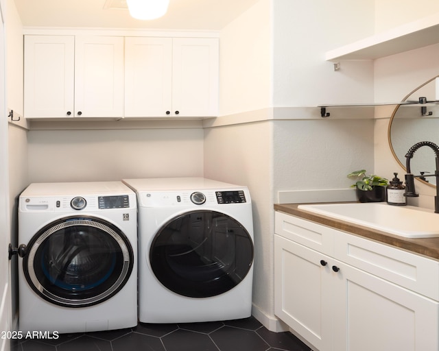 washroom featuring cabinet space, washing machine and clothes dryer, dark tile patterned flooring, and a sink