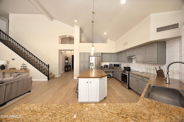 kitchen with stainless steel appliances, visible vents, a sink, light wood-type flooring, and gray cabinetry