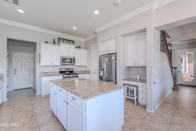 1128 E Phelps St, Gilbert, AZ 85295 - kitchen featuring appliances with stainless steel finishes, a kitchen island, tasteful backsplash, light tile patterned floors, and white cabinetry