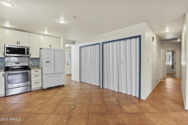 kitchen with visible vents, decorative backsplash, white cabinets, appliances with stainless steel finishes, and light tile patterned floors