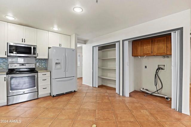 kitchen featuring decorative backsplash, white cabinets, appliances with stainless steel finishes, and light tile patterned floors