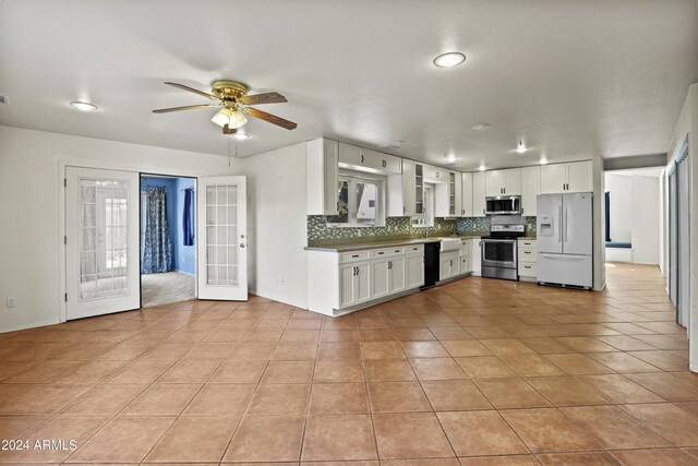 kitchen featuring ceiling fan, decorative backsplash, appliances with stainless steel finishes, white cabinets, and light tile patterned flooring
