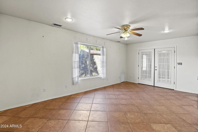 empty room with a ceiling fan, french doors, visible vents, and light tile patterned floors