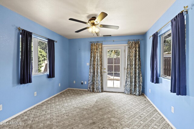 carpeted empty room featuring baseboards, ceiling fan, and visible vents