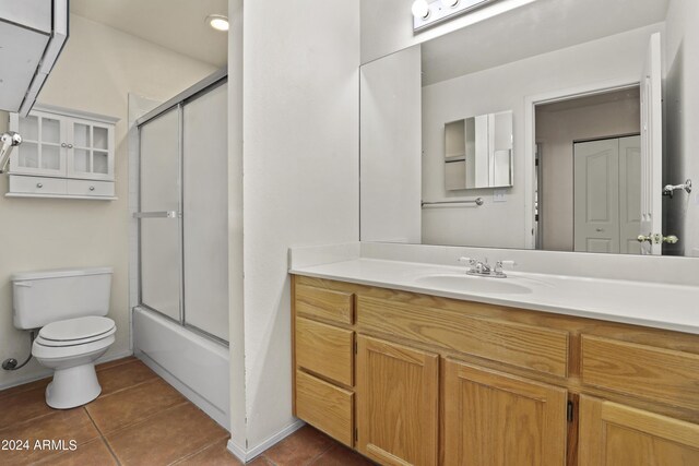 full bathroom with vanity, bath / shower combo with glass door, tile patterned floors, and toilet