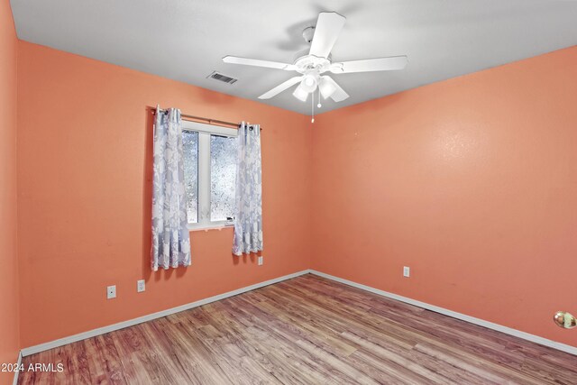 unfurnished room with visible vents, a ceiling fan, baseboards, and wood finished floors