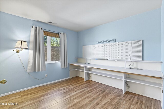 unfurnished office with baseboards, wood finished floors, and visible vents