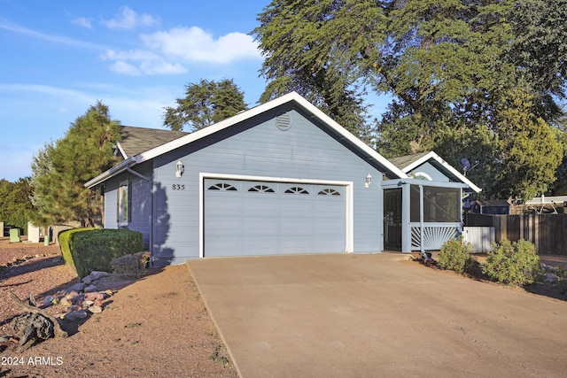 view of front of home featuring an attached garage, fence, a sunroom, and concrete driveway