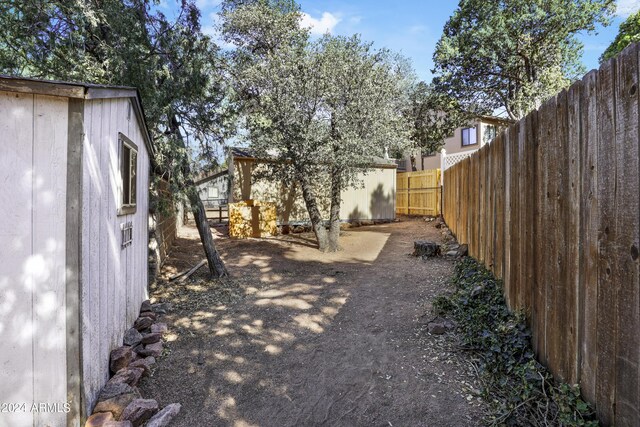 view of yard featuring an outdoor structure, a fenced backyard, and a storage shed