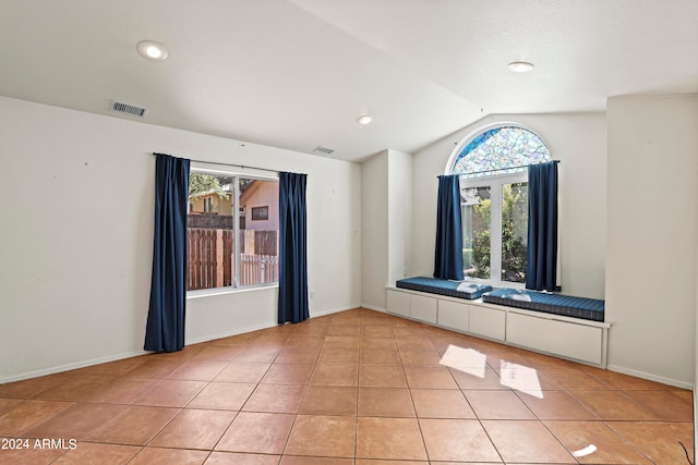 tiled spare room featuring lofted ceiling