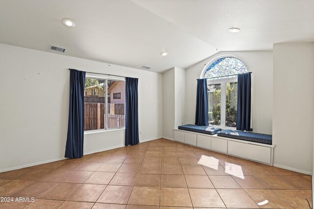 unfurnished room with light tile patterned floors, vaulted ceiling, and visible vents