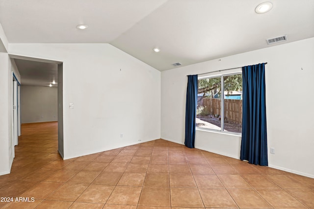 tiled spare room featuring vaulted ceiling