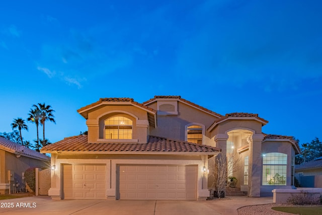 mediterranean / spanish house with driveway, a tile roof, and stucco siding