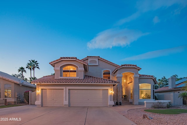 mediterranean / spanish-style home featuring driveway, an attached garage, a tiled roof, and stucco siding