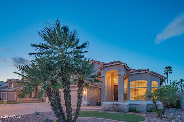 mediterranean / spanish-style home with driveway, a tiled roof, a garage, and stucco siding