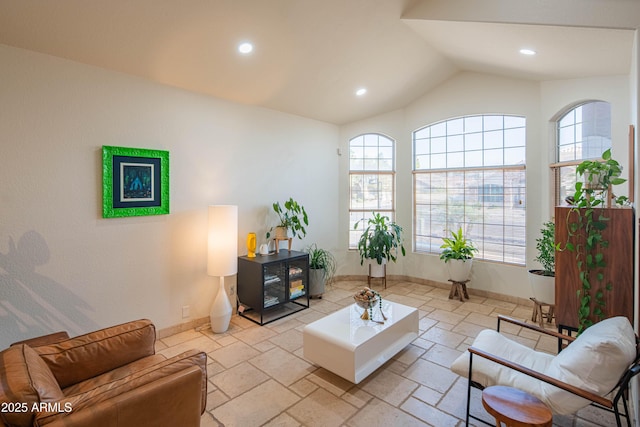 living room featuring lofted ceiling, stone tile flooring, and baseboards