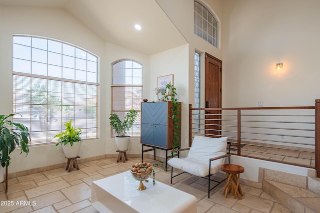 sitting room featuring high vaulted ceiling, recessed lighting, stone tile flooring, and baseboards