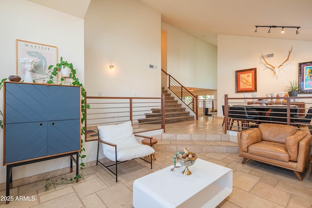 interior space featuring stairway, visible vents, high vaulted ceiling, and stone tile flooring