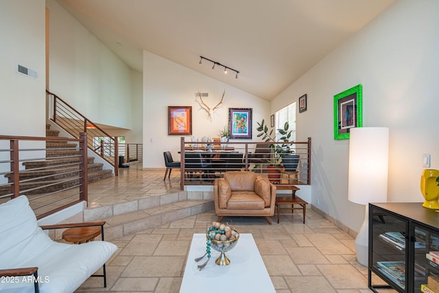 living area featuring baseboards, high vaulted ceiling, visible vents, and stone tile floors