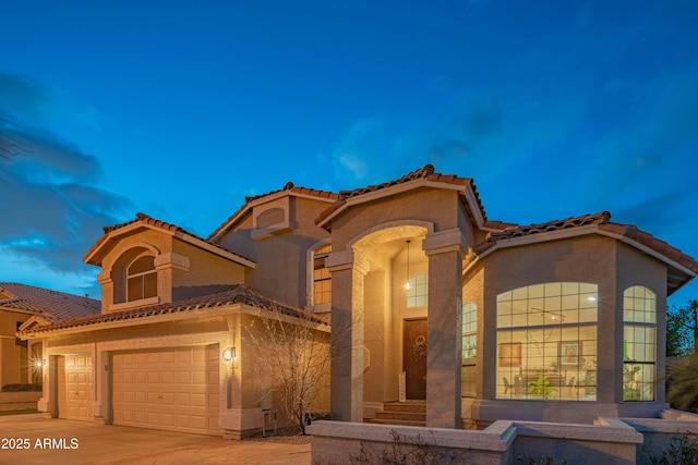 mediterranean / spanish house with a tile roof, driveway, and stucco siding