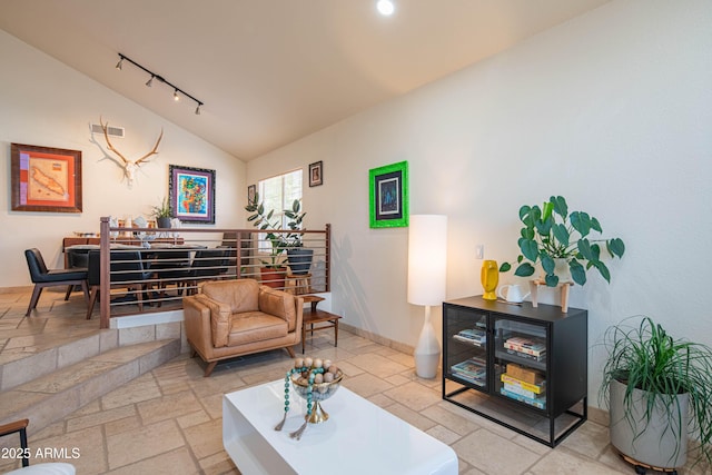 living area with stone tile floors, lofted ceiling, visible vents, rail lighting, and baseboards