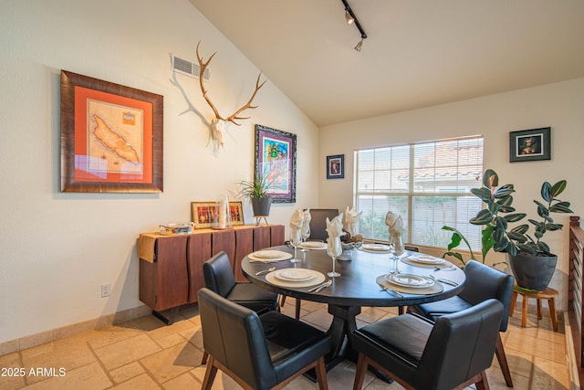 dining space featuring lofted ceiling, stone tile flooring, visible vents, track lighting, and baseboards