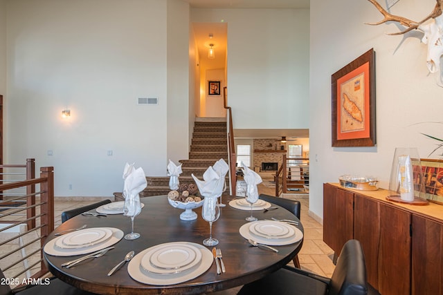 dining space with visible vents, a fireplace, stairway, and baseboards