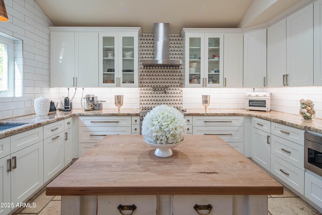 kitchen with lofted ceiling, backsplash, and wall chimney exhaust hood