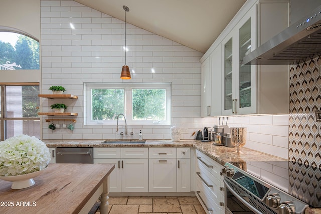 kitchen featuring stone tile floors, appliances with stainless steel finishes, vaulted ceiling, extractor fan, and a sink