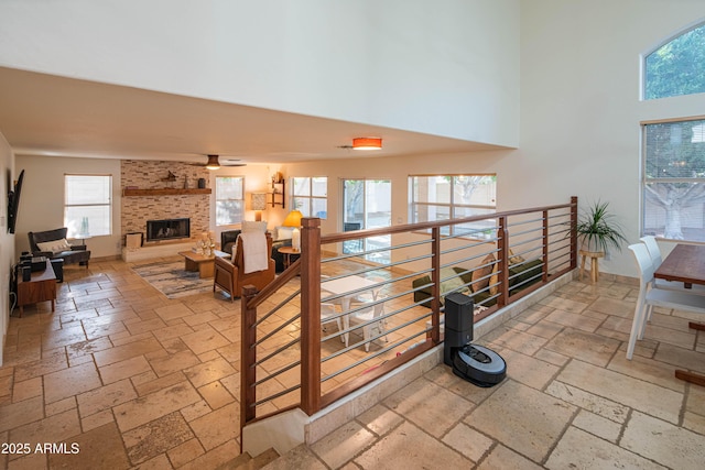 hallway featuring a wealth of natural light, baseboards, a towering ceiling, and stone tile floors