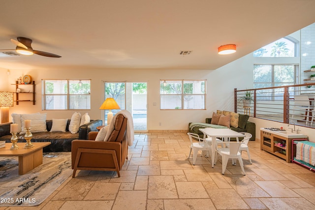 living area with a ceiling fan, visible vents, and stone tile floors