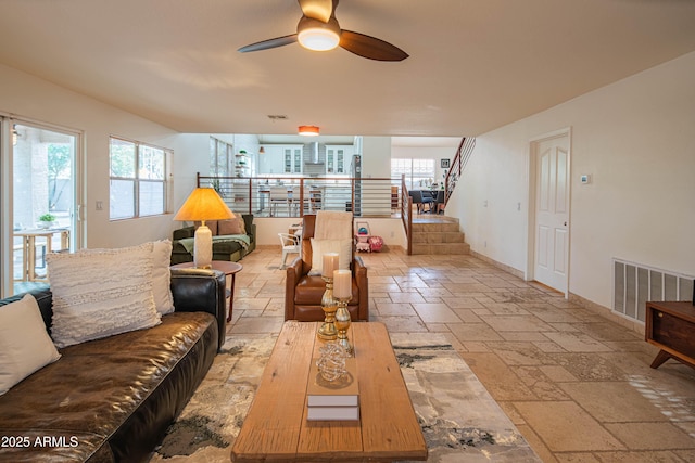 living area featuring a wealth of natural light, stairway, stone tile flooring, and visible vents