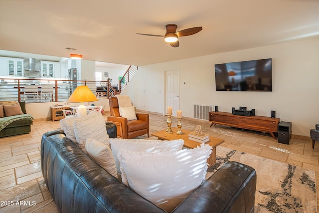 living room with stairs, baseboards, visible vents, and stone tile floors