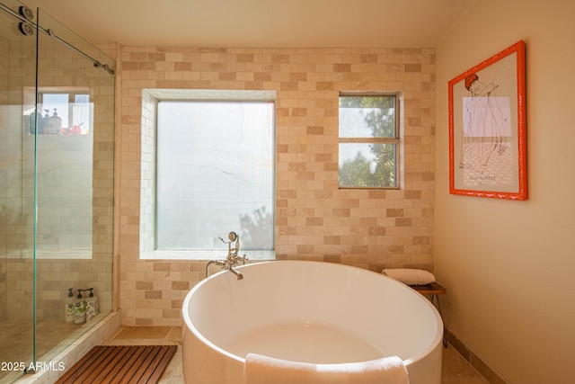 full bath featuring a stall shower, a freestanding tub, and baseboards