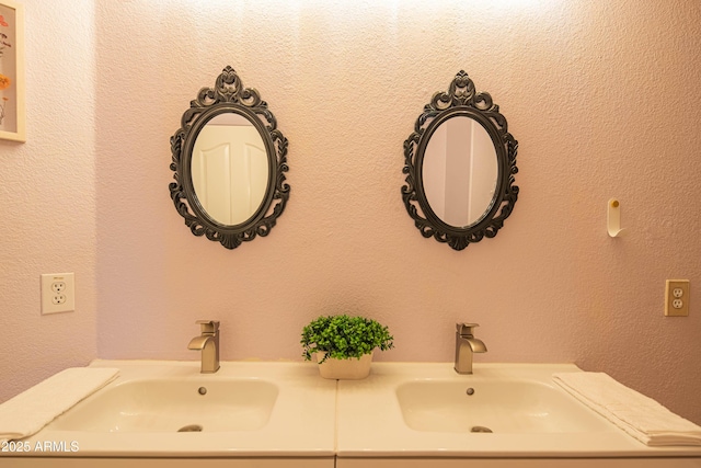 bathroom featuring a textured wall, double vanity, and a sink