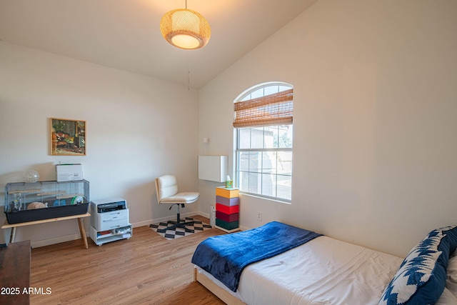 bedroom featuring lofted ceiling, wood finished floors, and baseboards