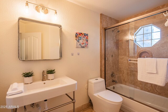 bathroom featuring combined bath / shower with glass door, a sink, and toilet