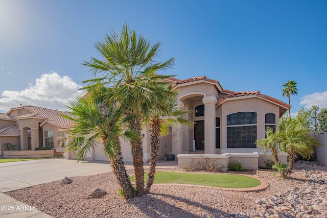 mediterranean / spanish home featuring an attached garage, a tile roof, concrete driveway, and stucco siding