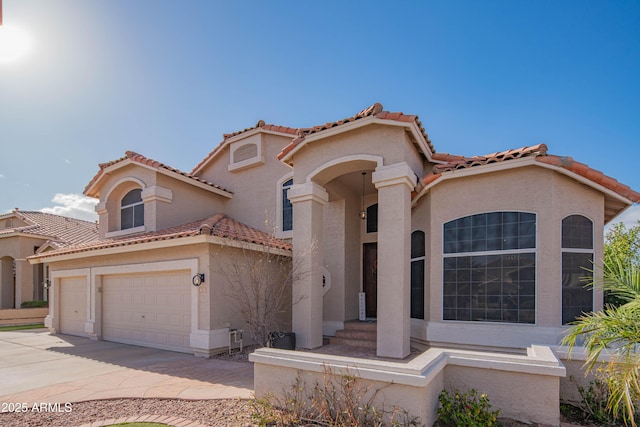 mediterranean / spanish-style home with a garage, driveway, a tile roof, and stucco siding