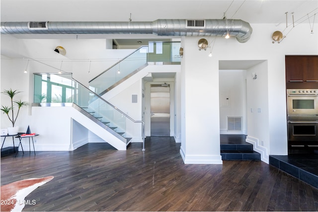 unfurnished living room featuring dark hardwood / wood-style floors and a high ceiling