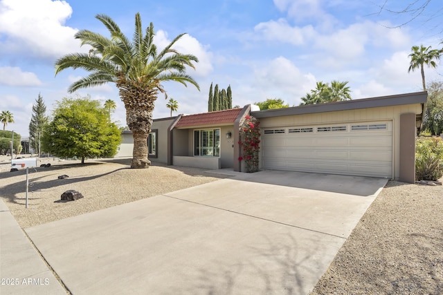 single story home featuring a garage, concrete driveway, a tiled roof, and stucco siding