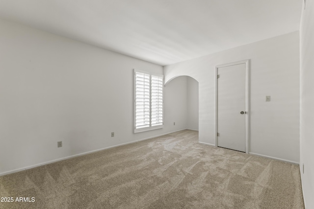 spare room featuring light colored carpet and baseboards