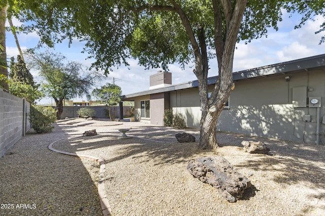 rear view of property featuring a patio area, a fenced backyard, and a chimney