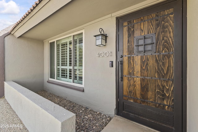 doorway to property featuring stucco siding and a tiled roof